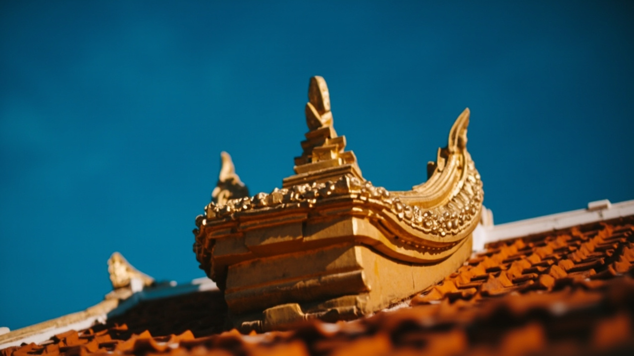 Close-up of an ornate gold finial of the Phnom Penh Royal Palace roof against a deep blue sky